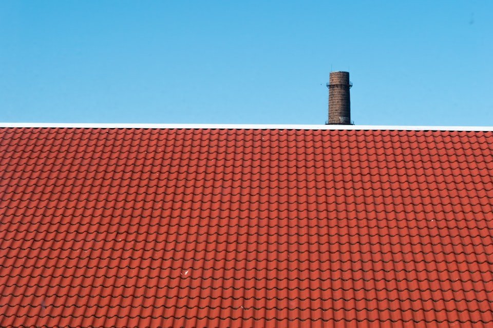 Neu gedecktes Ziegeldach mit Kamin vor blauem Himmel