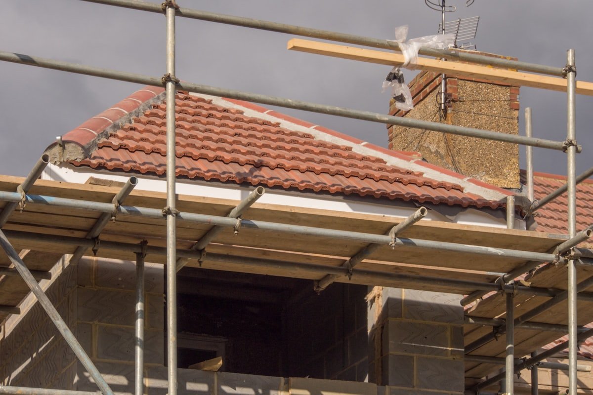 Eingerüstetes Haus, die neuen Ziegel liegen, der Kamin wird angeschlossen